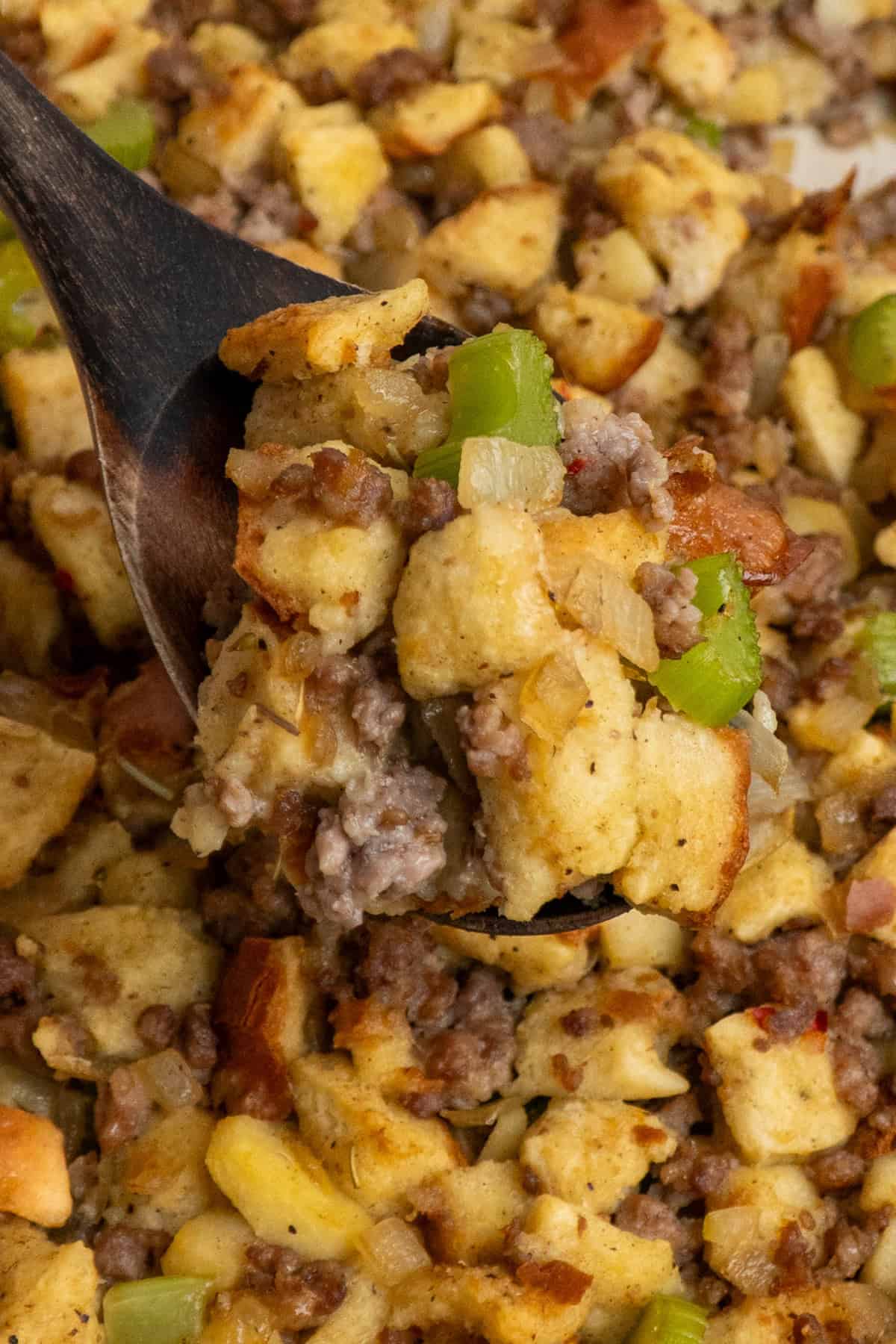 A wooden spoon holding a scoop of sausage stuffing.