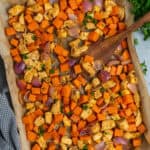 Sheet pan chicken and sweet potatoes with a wooden spatula ready to be served.