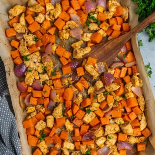 Sheet pan chicken and sweet potatoes with a wooden spatula ready to be served.