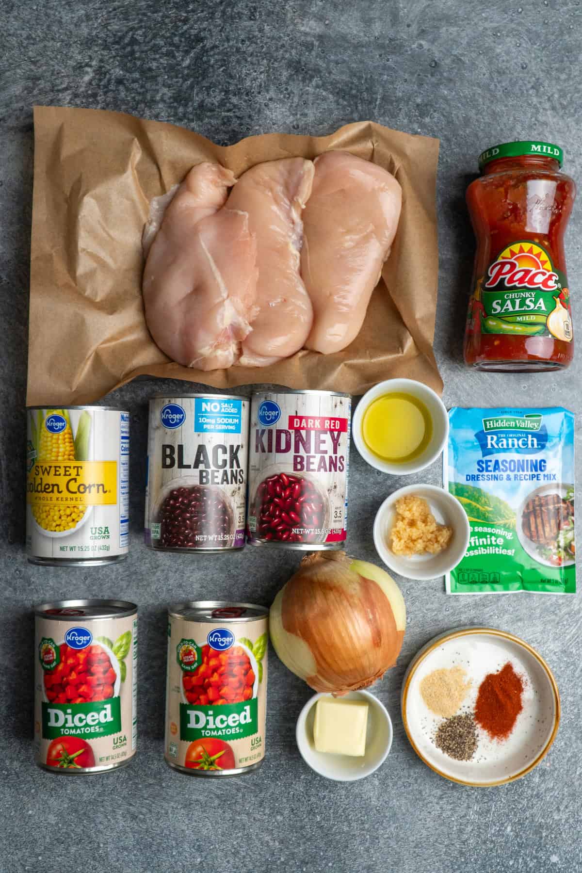 Ingredients to make chicken taco soup on a gray stone countertop.