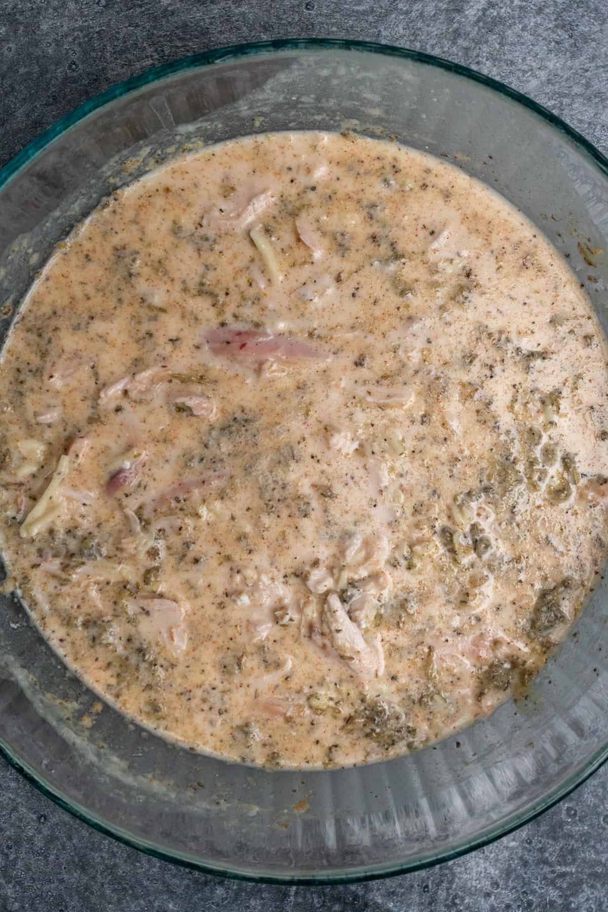 Chicken, rice, and seasonings mixed together with the wet ingredients.