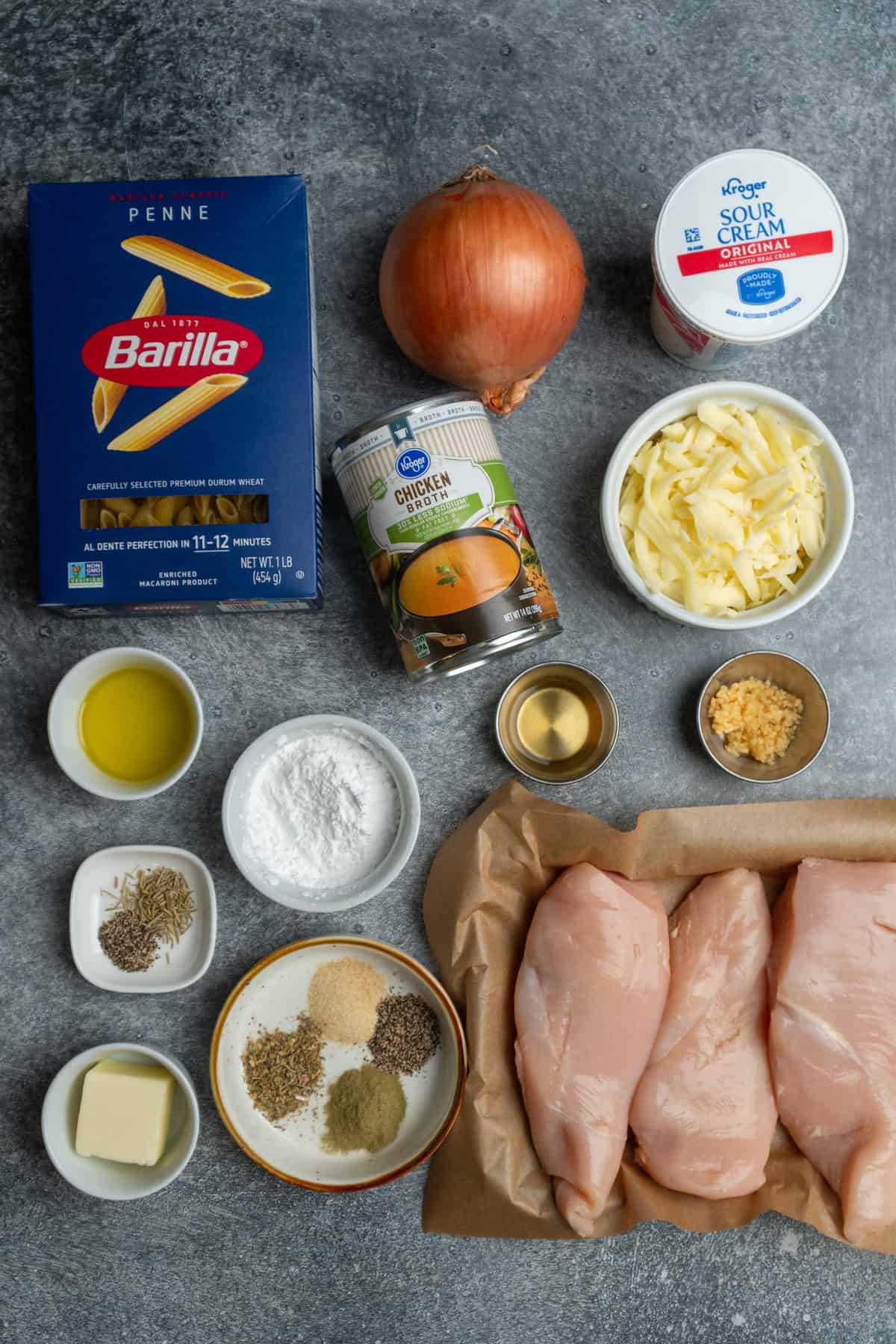 Ingredients to make French onion chicken pasta on a gray countertop.