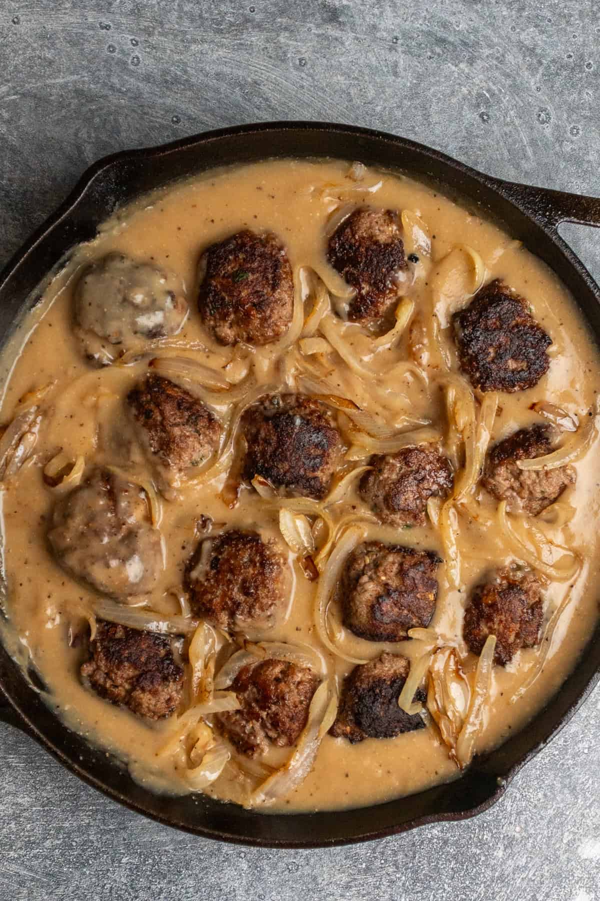 Meatballs and onions added into the gravy and ready to simmer.