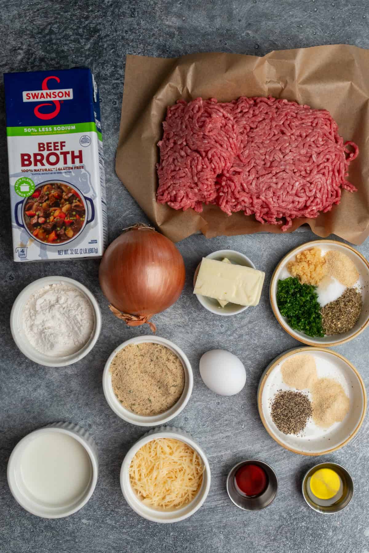 Ingredients to make meatballs and gravy on a gray stone countertop.