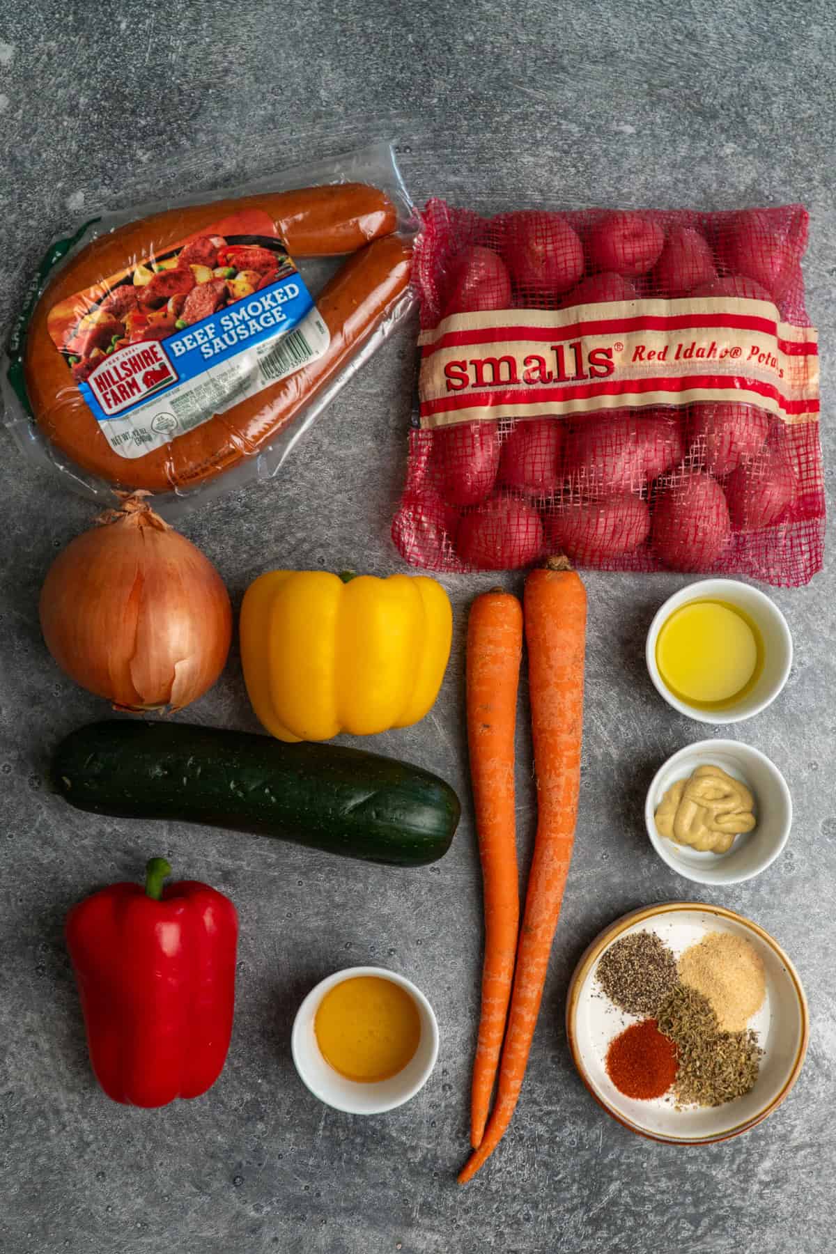 Ingredients to make sausage and veggies on a gray stone countertop.