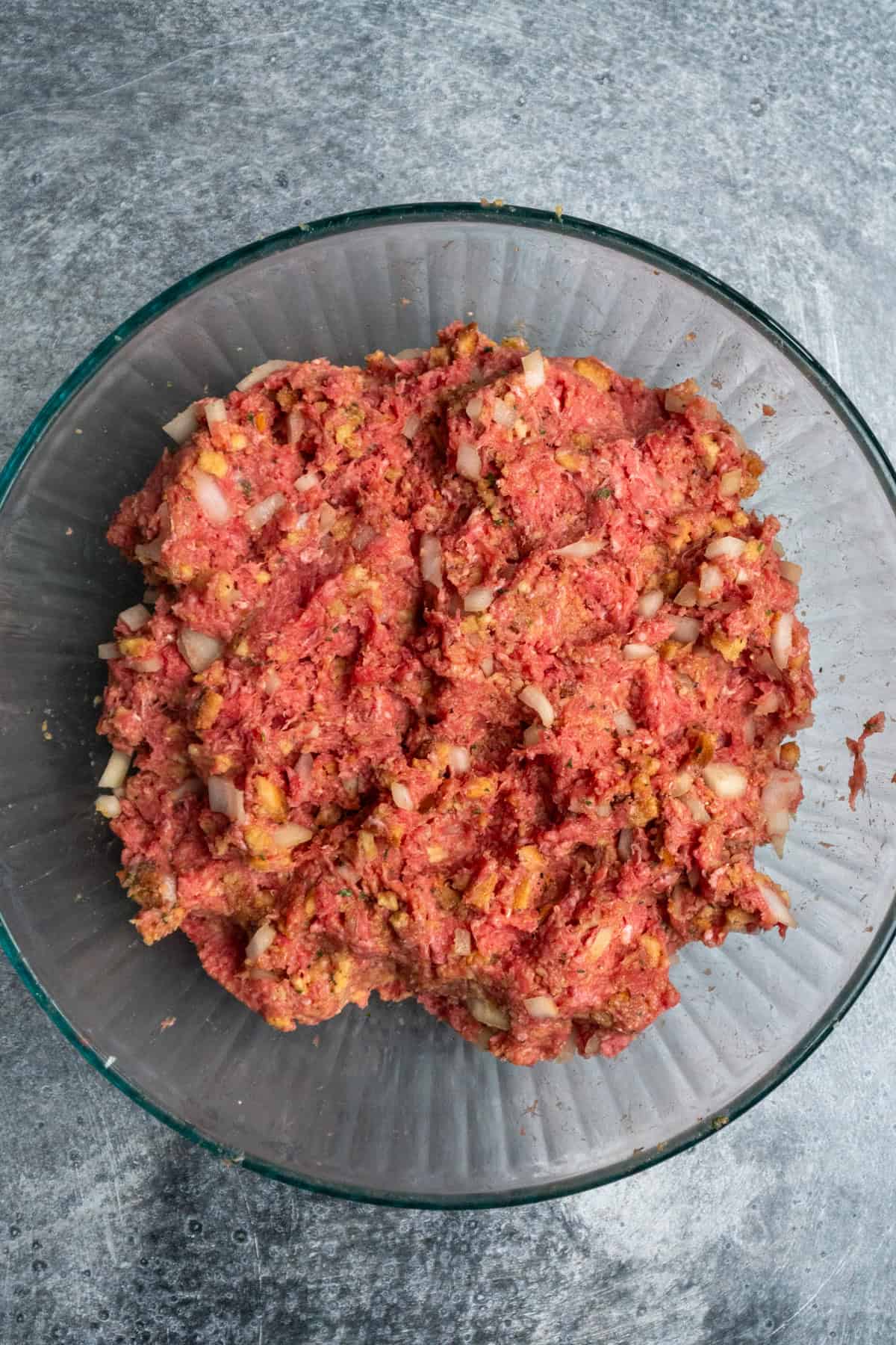 Meatloaf ingredients mixed together in a clear mixing bowl.