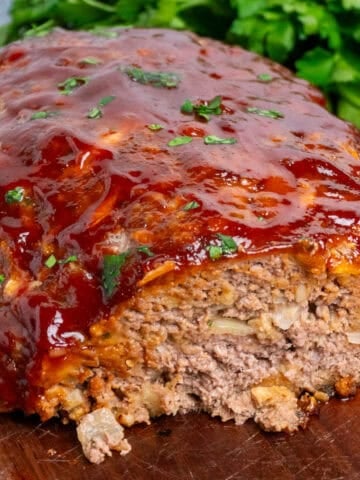 Stove Top stuffing meatloaf with a slice cut off on a wood cutting board.