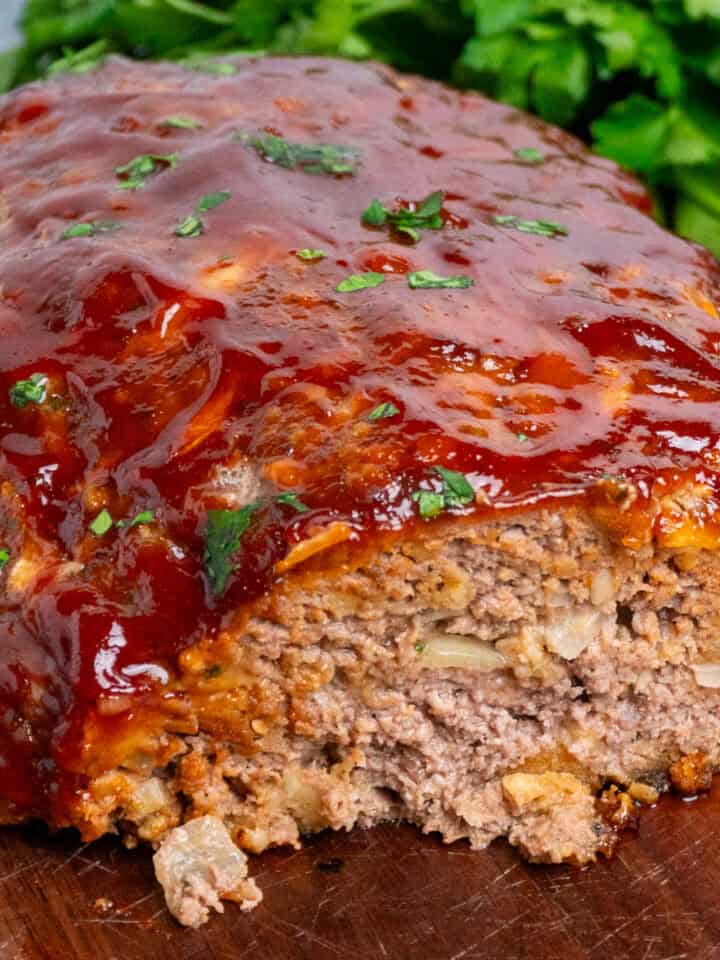 Stove Top stuffing meatloaf with a slice cut off on a wood cutting board.