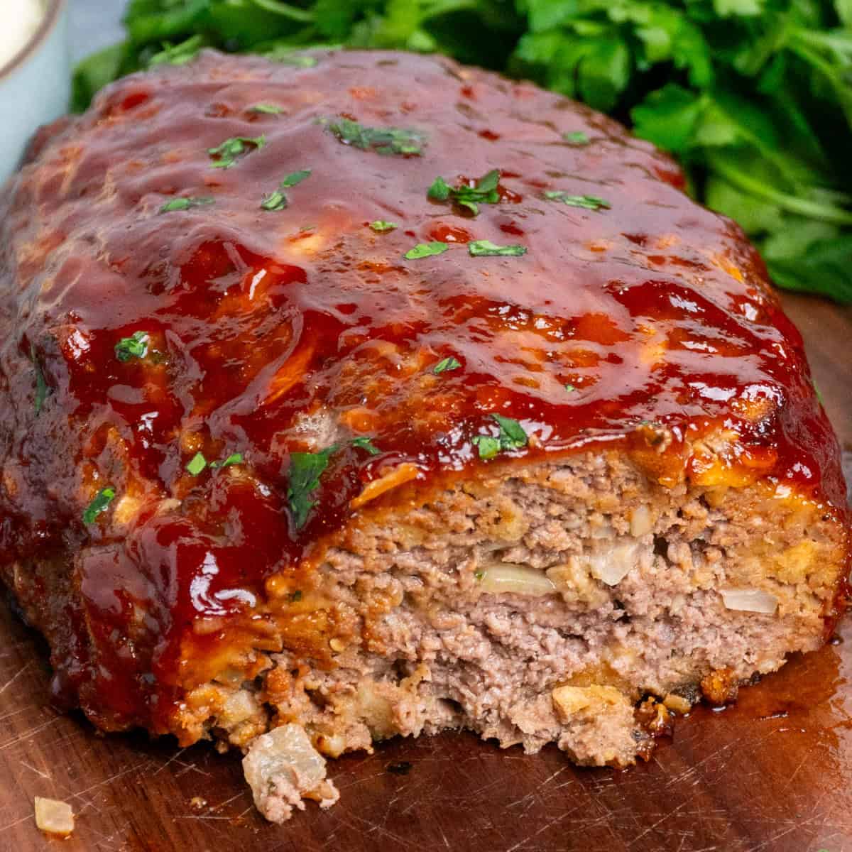 Stove Top stuffing meatloaf with a slice cut off on a wood cutting board.