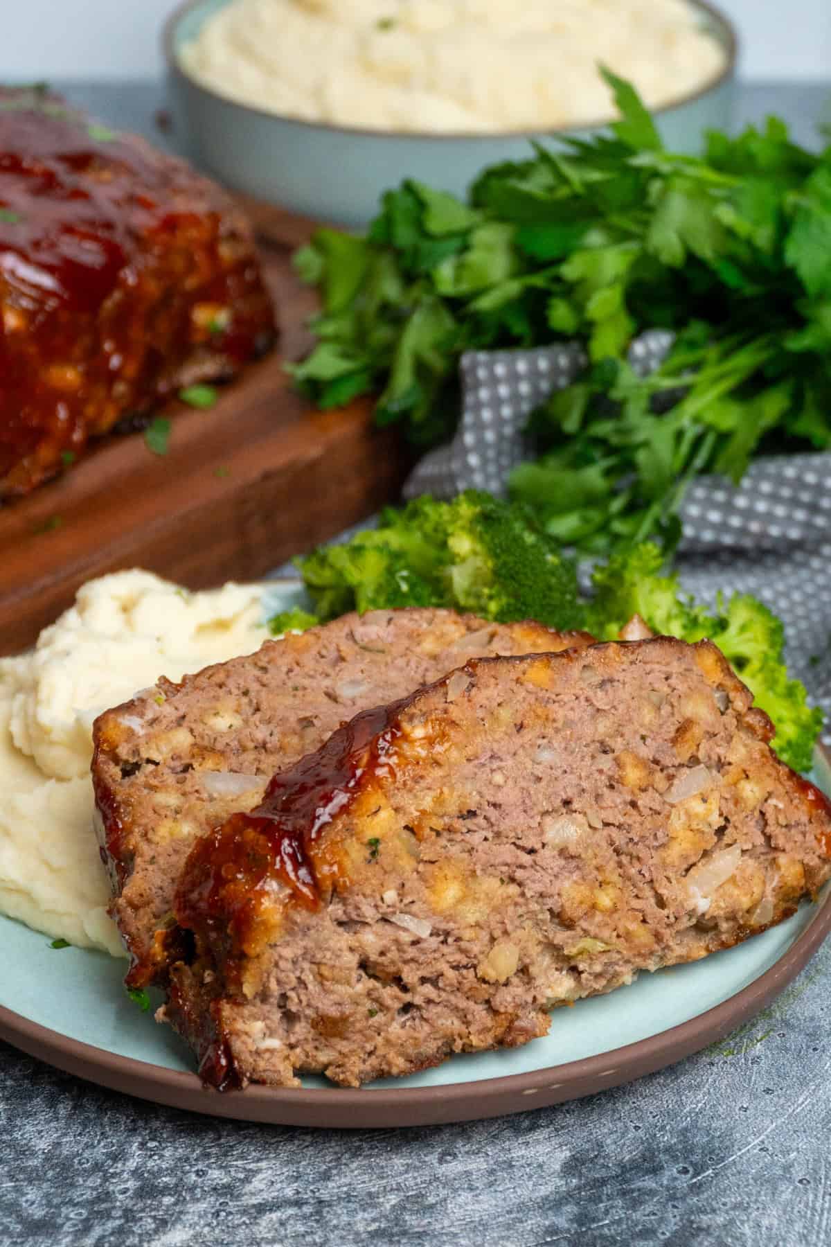 Two slice of Stove Top stuffing meatloaf on a plate of mashed potatoes.
