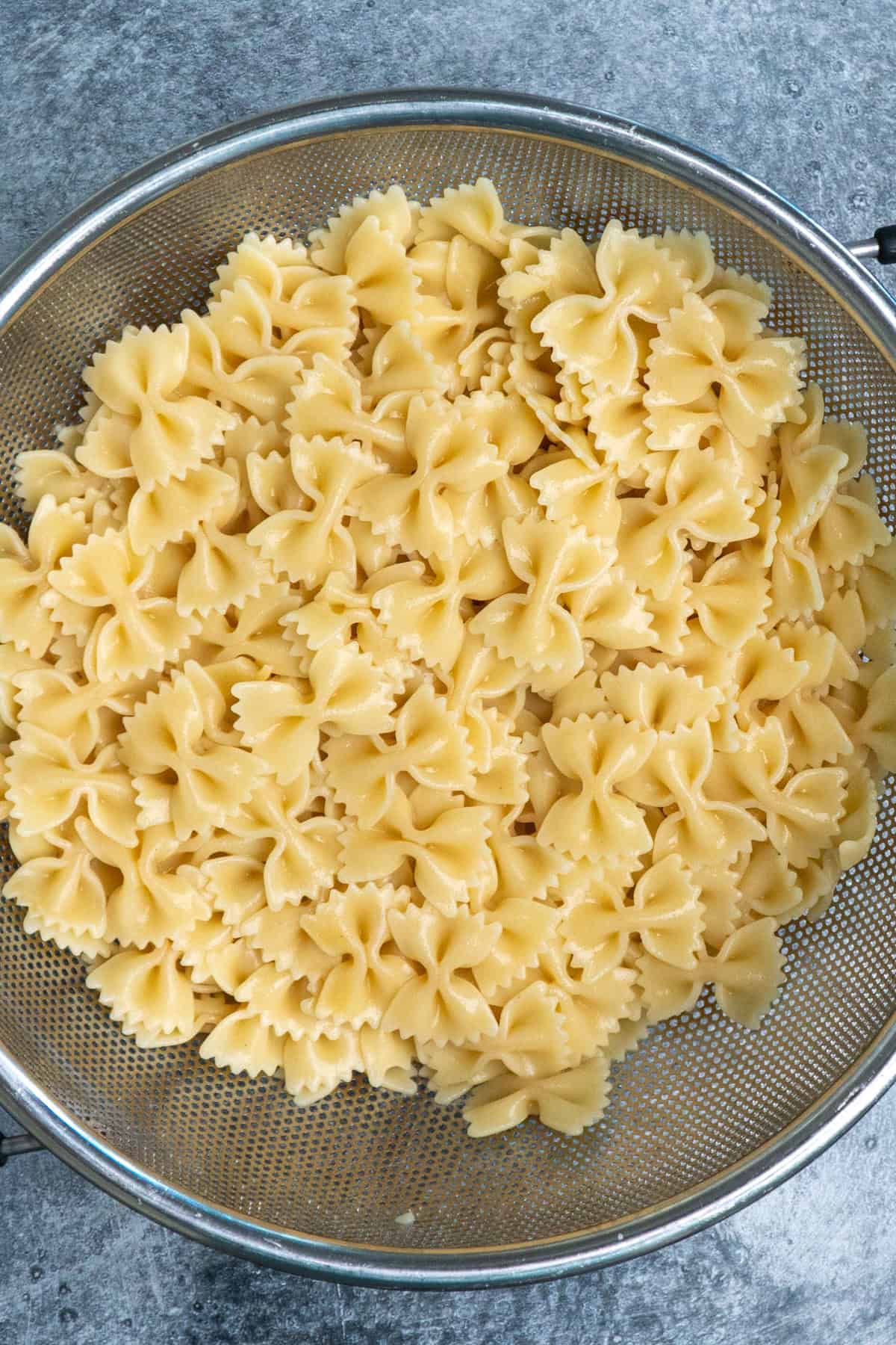 Cooked and drained farfalle pasted in a strainer.