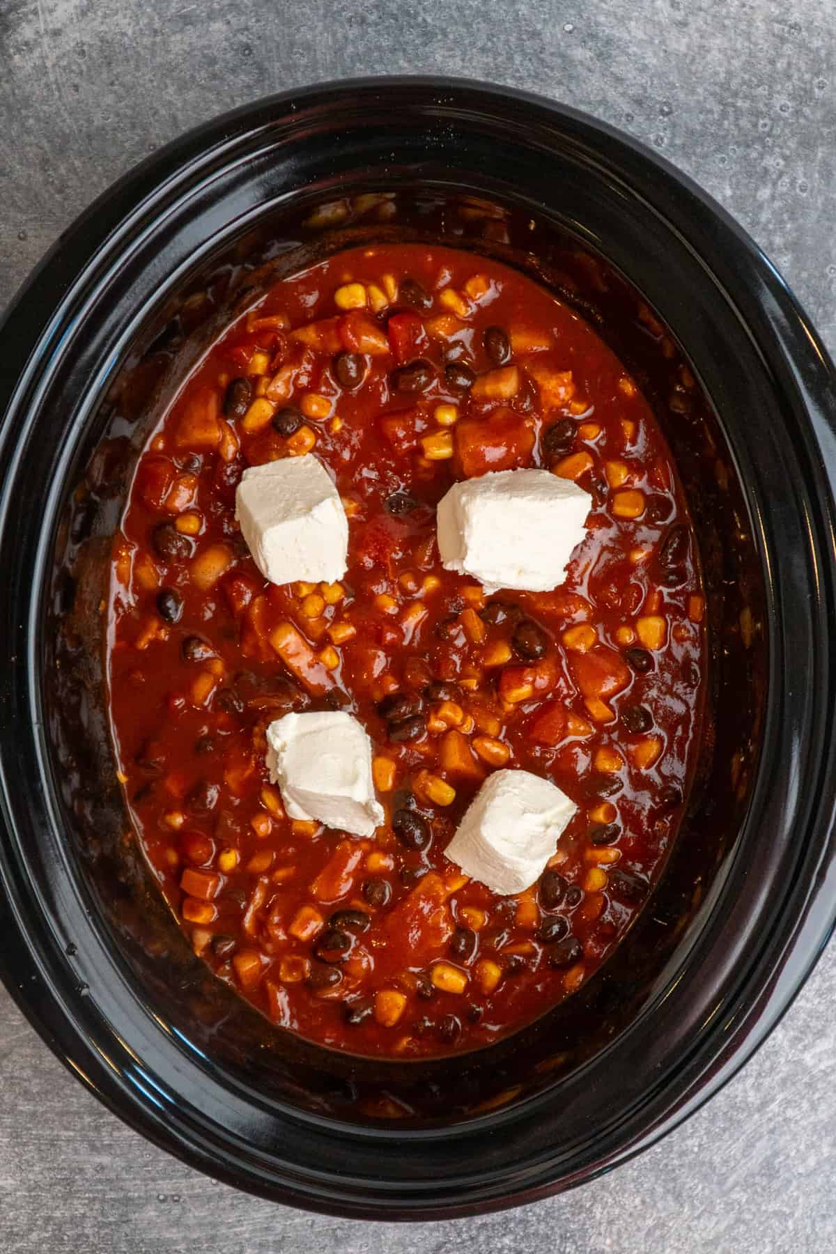 Chicken, taco seasoning, diced onion, black beans, corn, Rotel, and cream cheese to the slow cooker and mixed together.