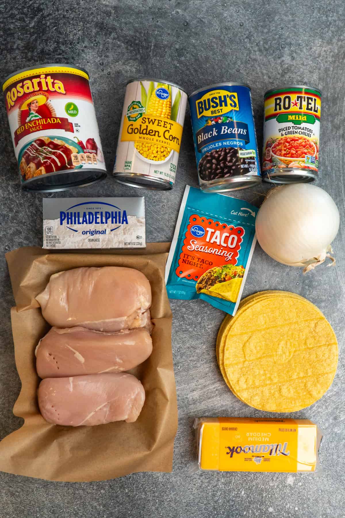 Ingredients to make chicken enchilada casserole on a gray countertop.