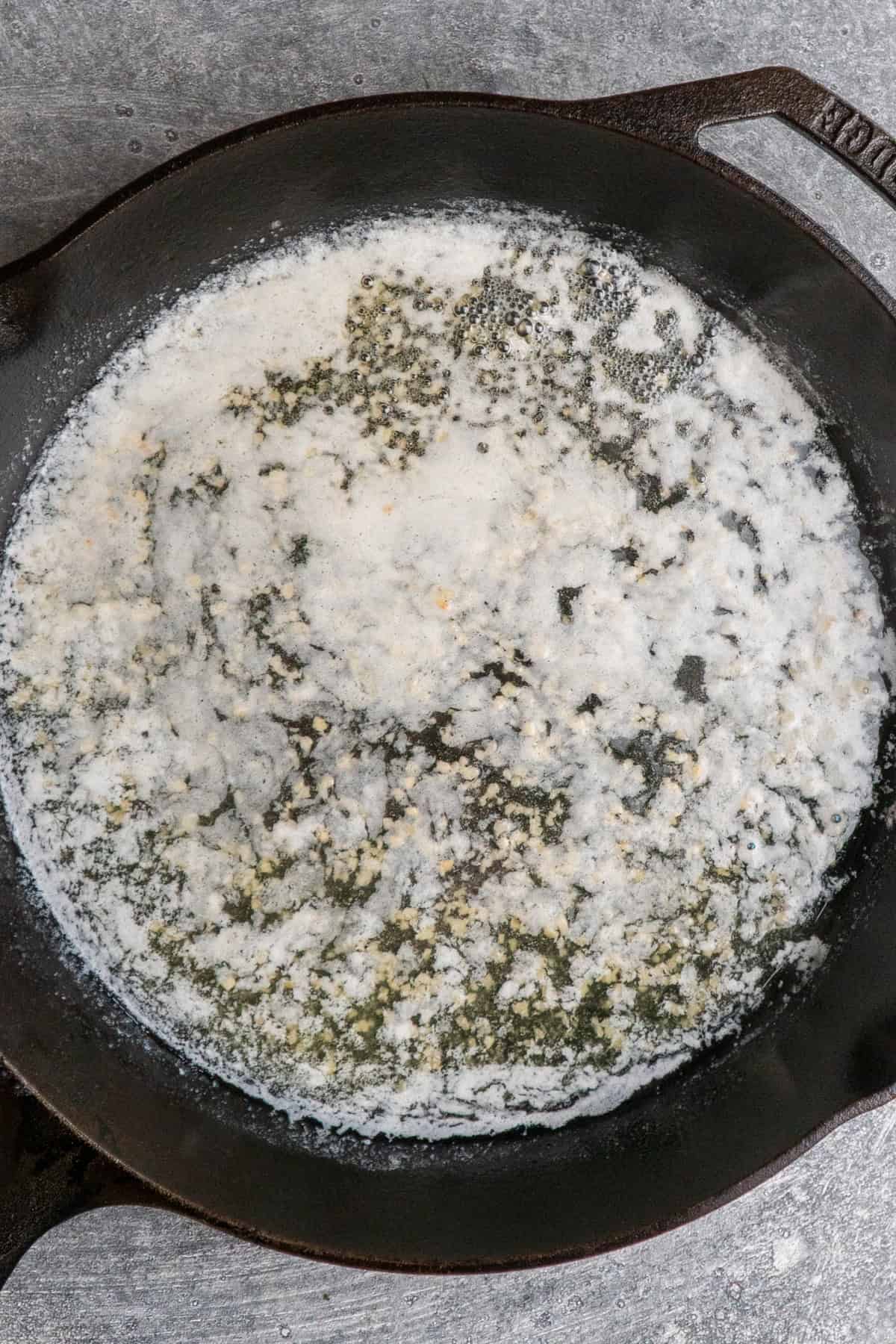 Garlic cooking in butter on a skillet.