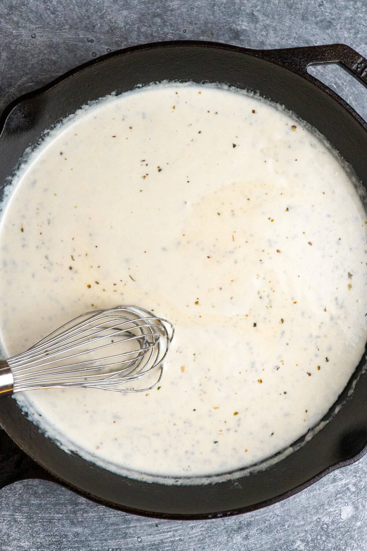 Heavy cream, onion powder, black pepper, and Italian seasoning added to the skillet.