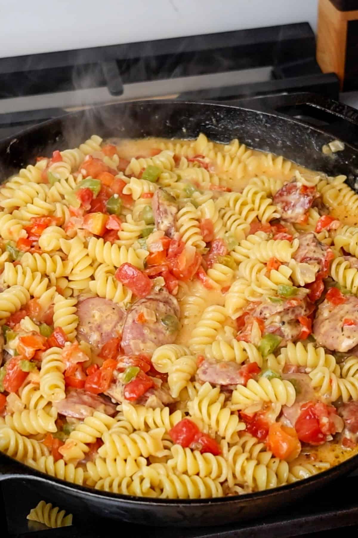 Pasta added to cheese sauce, veggies and sausage.