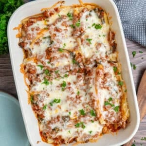 String cheese manicotti in a baking dish and garnished with parsley.