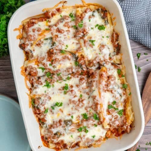 String cheese manicotti in a baking dish and garnished with parsley.