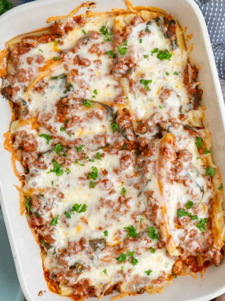 String cheese manicotti in a baking dish and garnished with parsley.