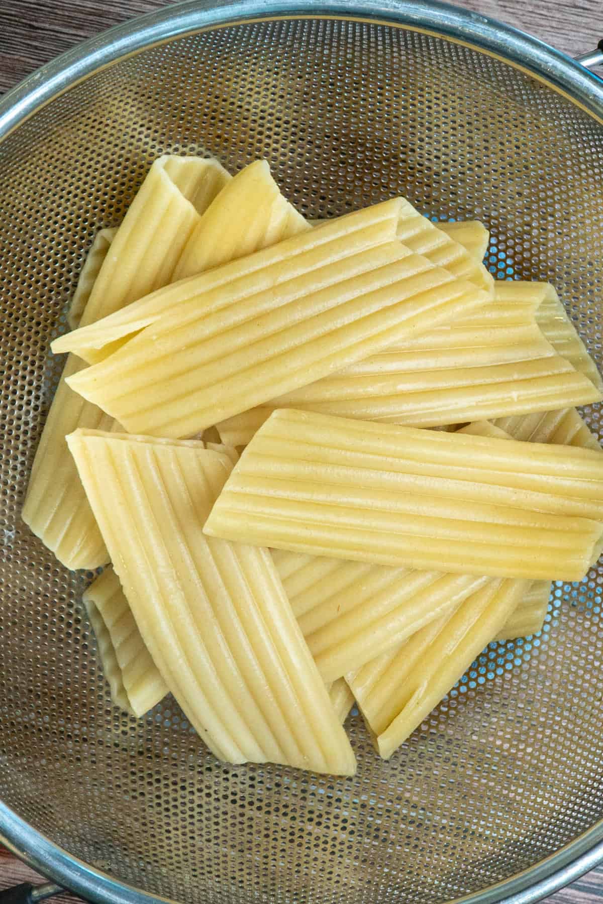 Manicotti shells cooked and drained in a strainer.