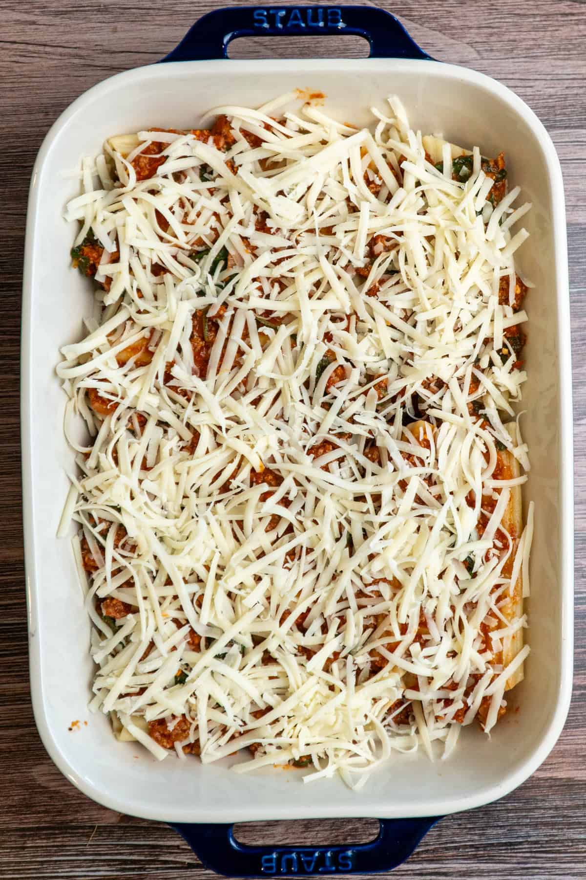 Grated mozzarella cheese over the top of the manicotti and ready to bake.