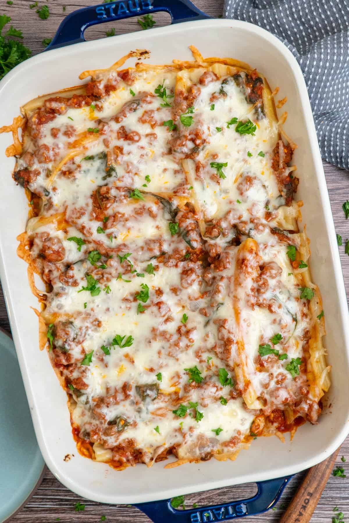 String cheese manicotti in a baking dish and garnished with parsley.