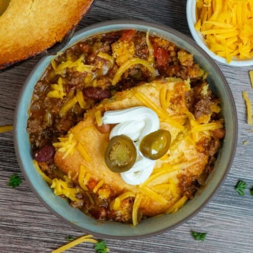 Chili cornbread casserole in a bowl and garnished with sour cream and jalapenos.