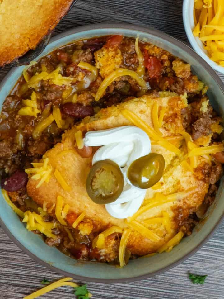 Chili cornbread casserole in a bowl and garnished with sour cream and jalapenos.