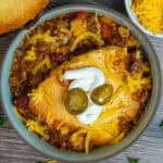 Chili cornbread casserole in a bowl and garnished with sour cream and jalapenos.