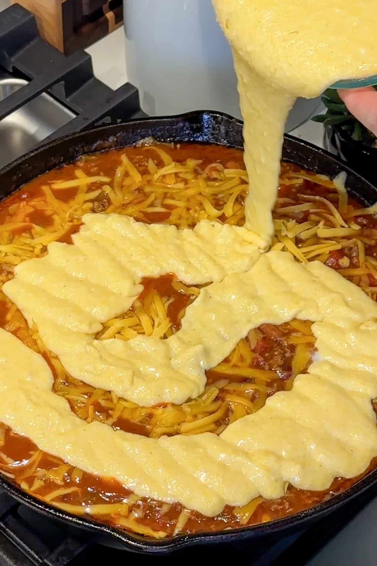 Cheese and cornbread added to the chili in the skillet.
