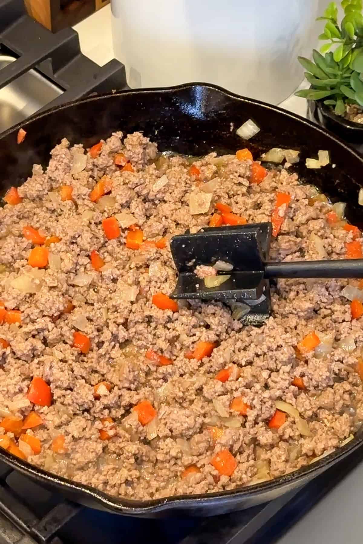 Ground beef being cooked with onions and bell peppers.