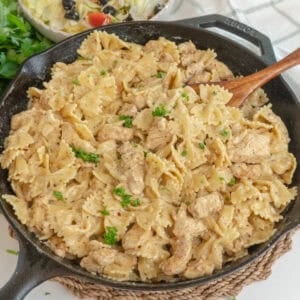 Garlic parmesan pasta chicken in a skillet with a wooden spoon ready to serve.