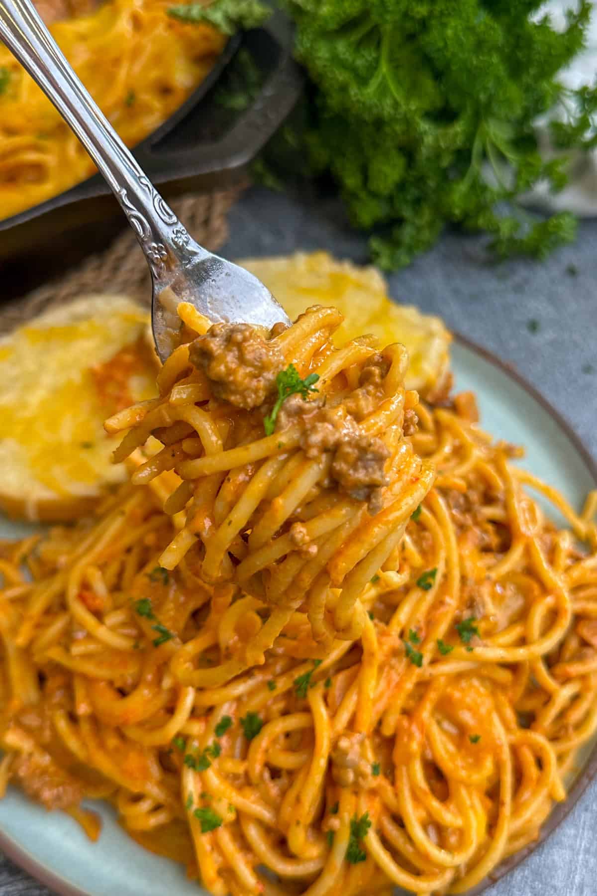A fork holding a bite of cheesy baked spaghetti.