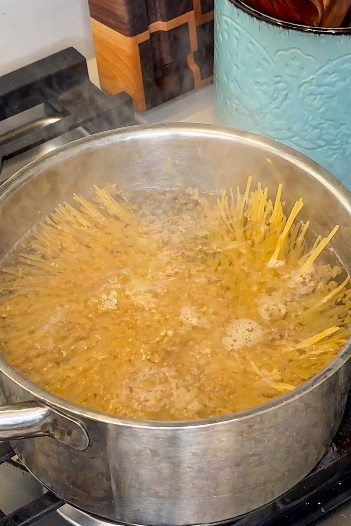 Spaghetti being cooked in a boiling pot of water.