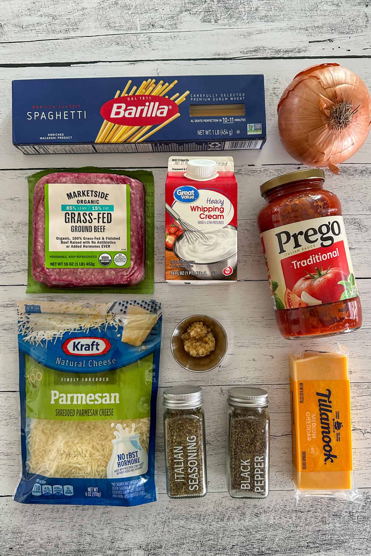 Ingredients to make cheesy baked spaghetti on a white wood countertop.