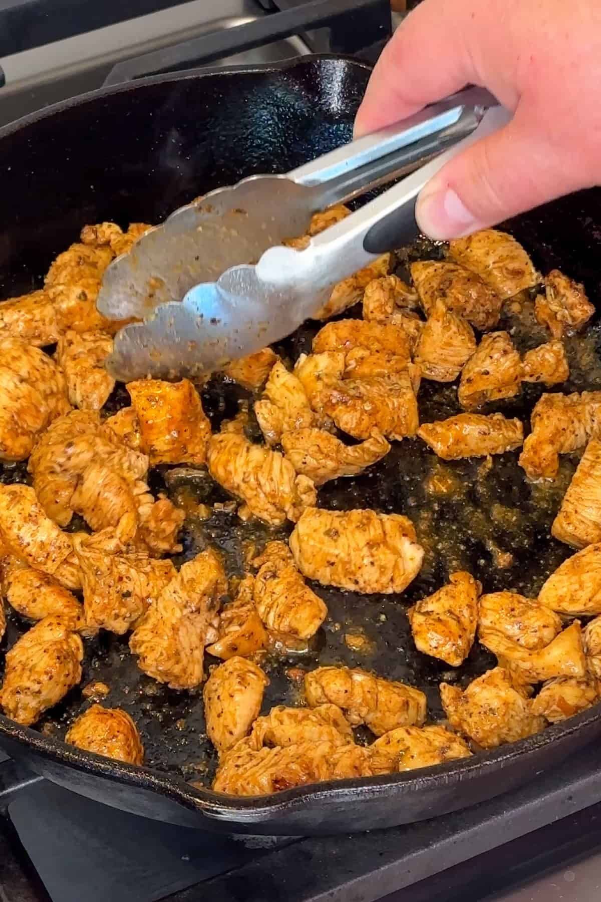 Seasoned chicken being cooked in a cast iron skillet.