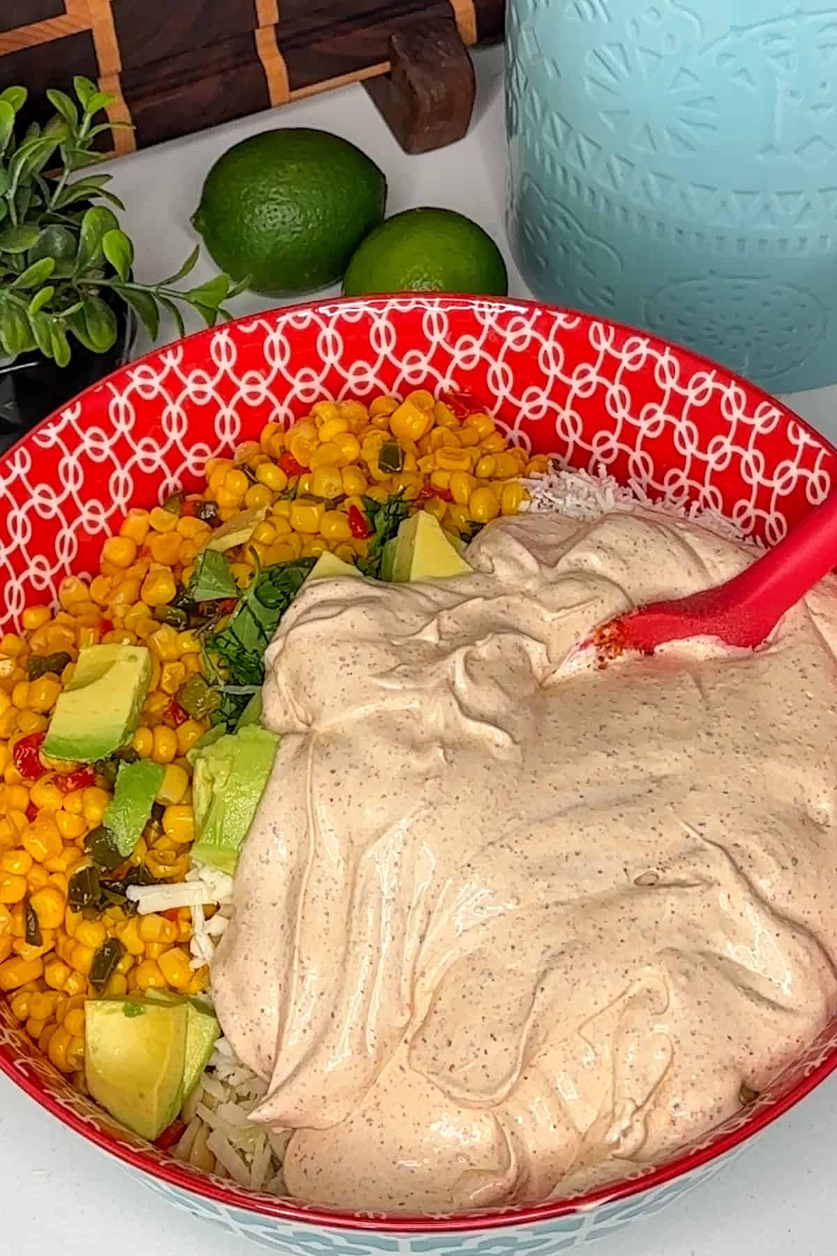 Pasta, veggies, and dressing in a colorful bowl, ready to be mixed together.