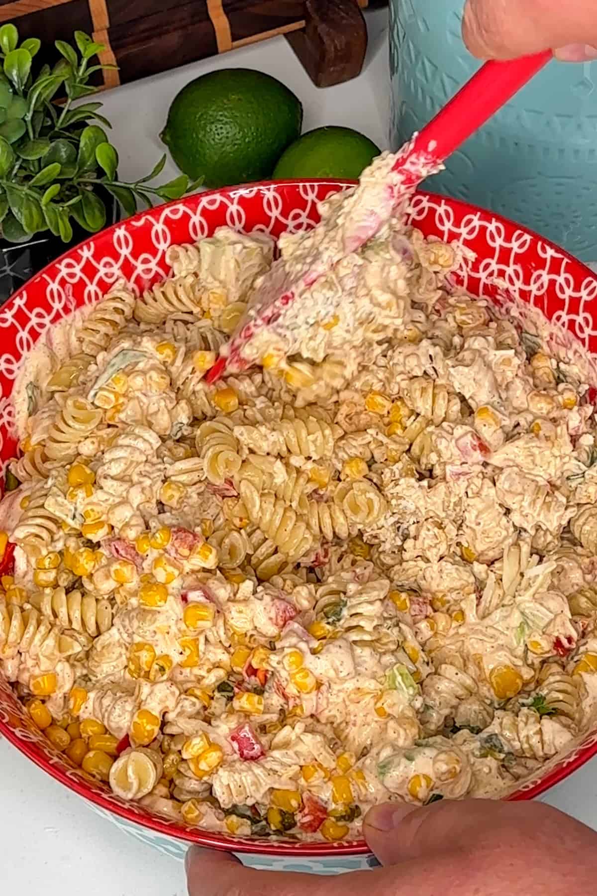 Mexican street corn pasta salad ingredients mixed together in a red colorful bowl.