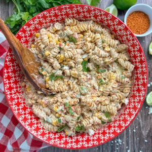 Mexican street corn pasta salad in a colorful bowl with a wooden spoon.