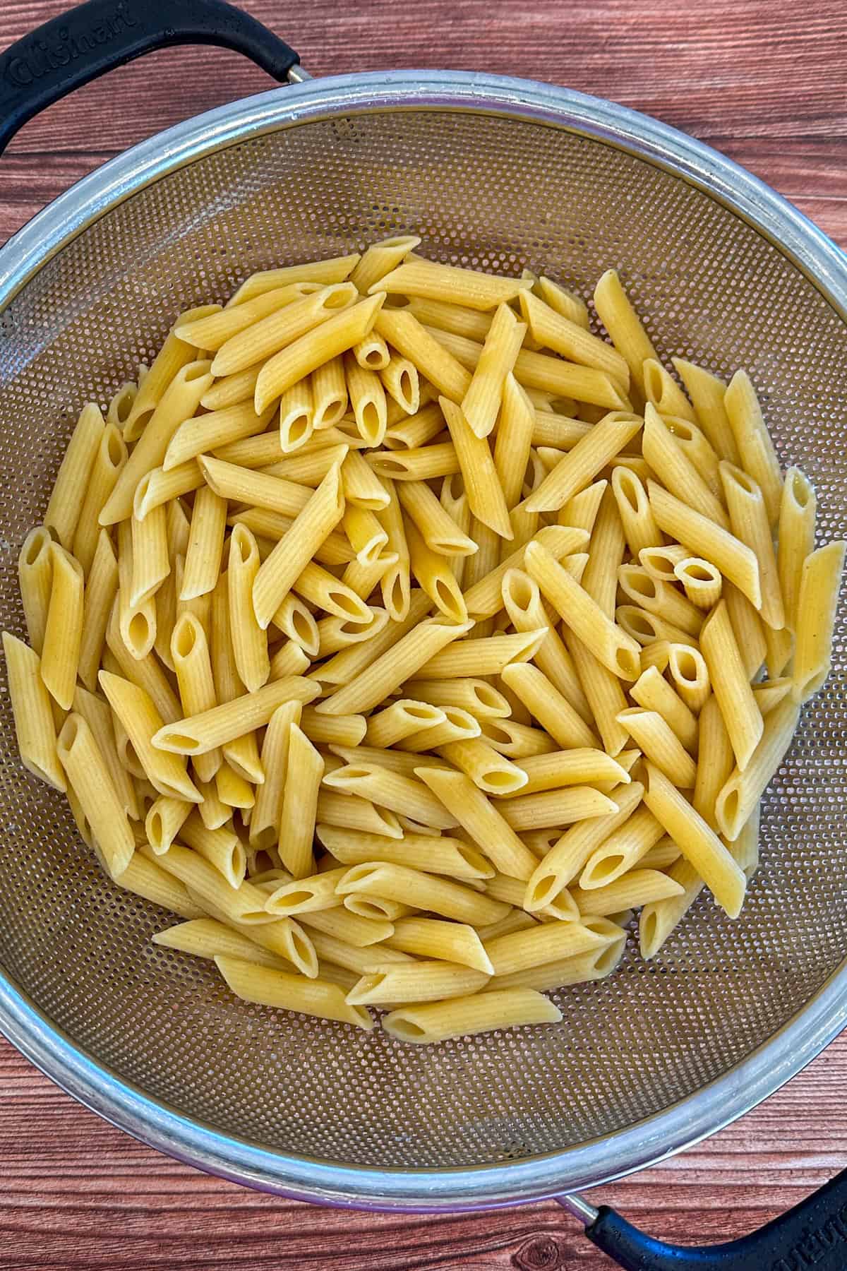 Cooked penne pasta in a colander.