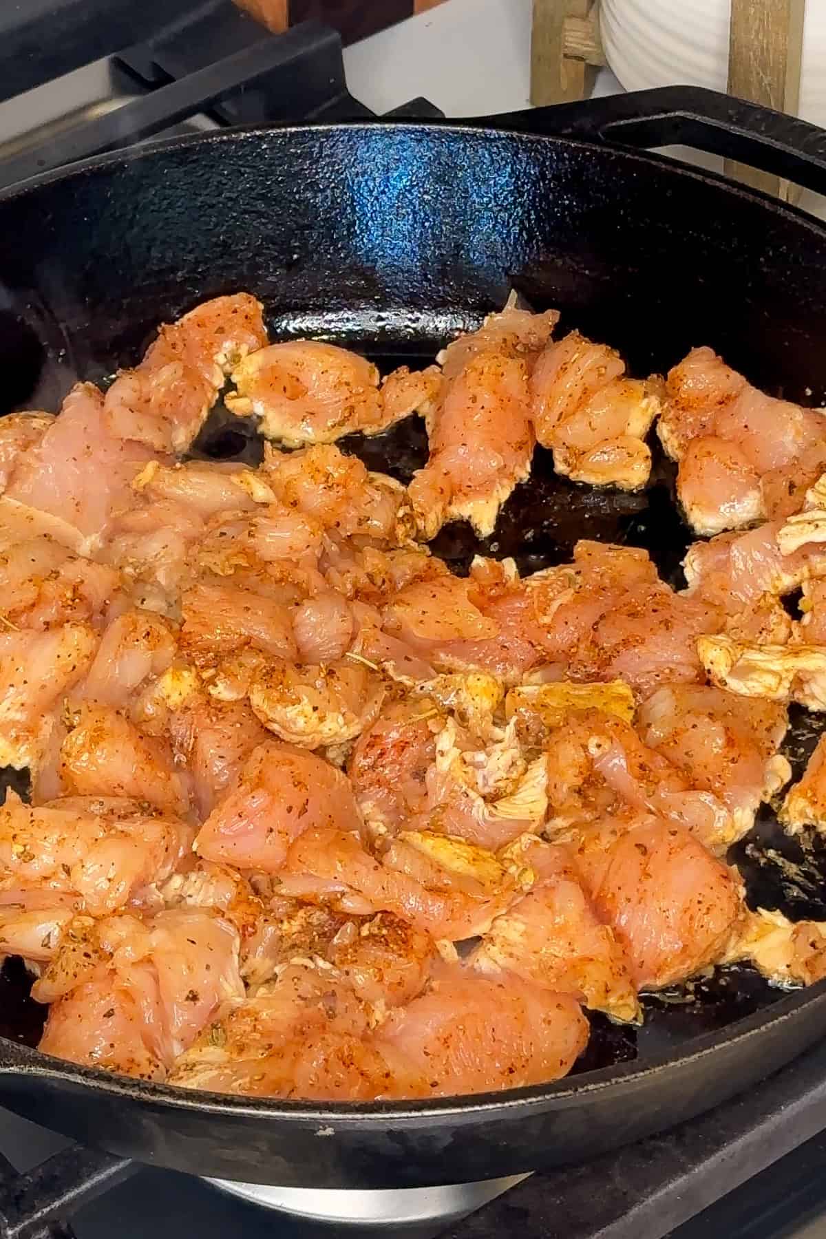 Seasoned chicken bites being cooked in a cast iron skillet.