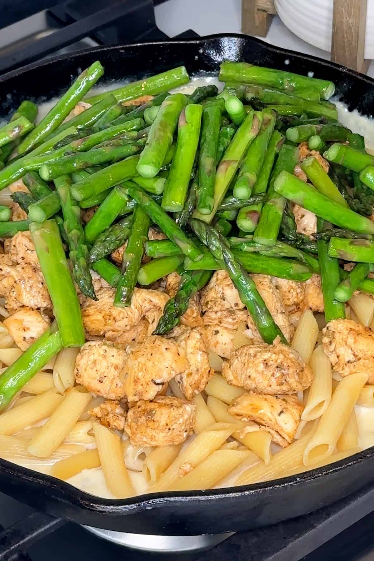 Cooked chicken, pasta, and asparagus added to the homemade alfredo sauce.