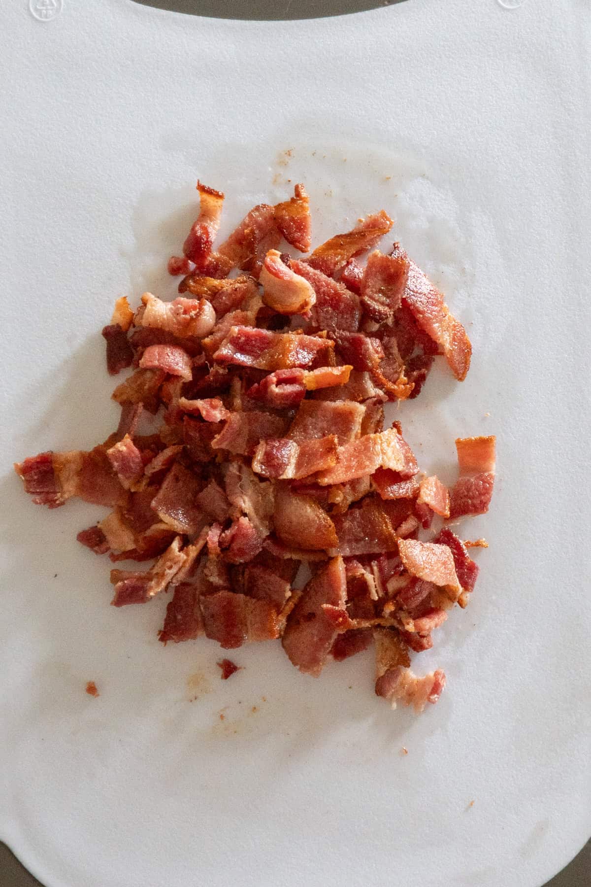 Cooked bacon chopped into pieces on a cutting board.