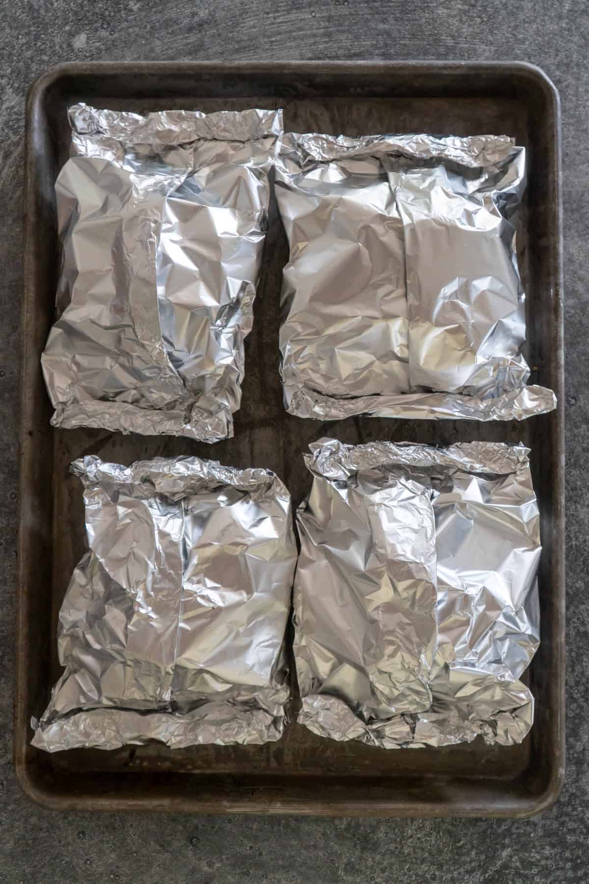 Foil packets sealed and placed on a baking sheet.