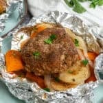 Hobo dinner in a foil packet opened on a plate.