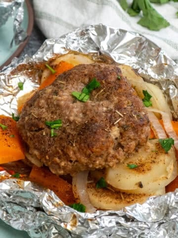 Hobo dinner in a foil packet opened on a plate.