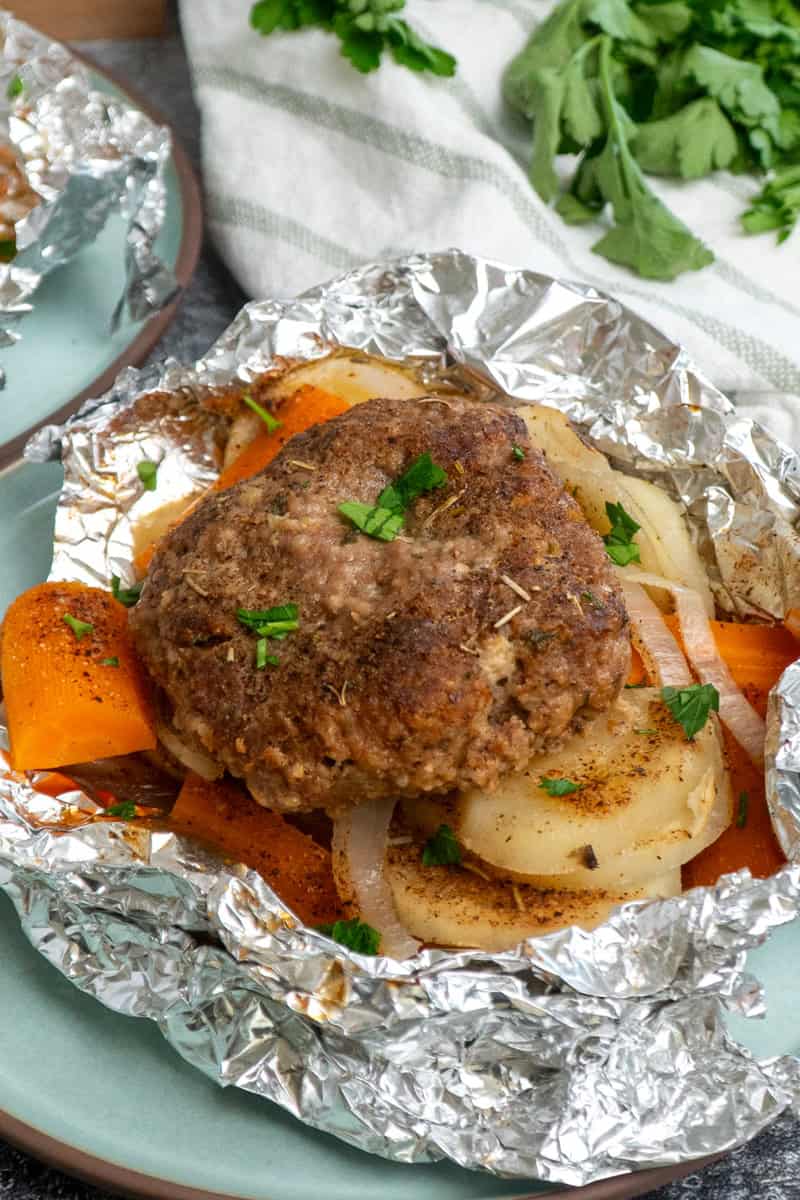 A foil dinner with beef, carrots, potatoes, and onions opened and ready to eat.