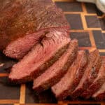 Smoked tri tip sliced on a wooden cutting board.