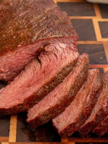 Smoked tri tip sliced on a wooden cutting board.