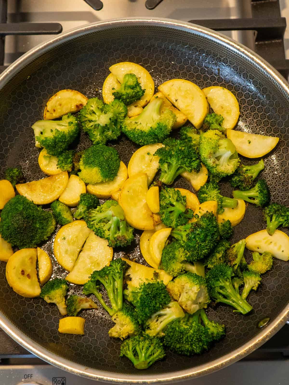 Broccoli and yellow squash sautéed in a skillet.